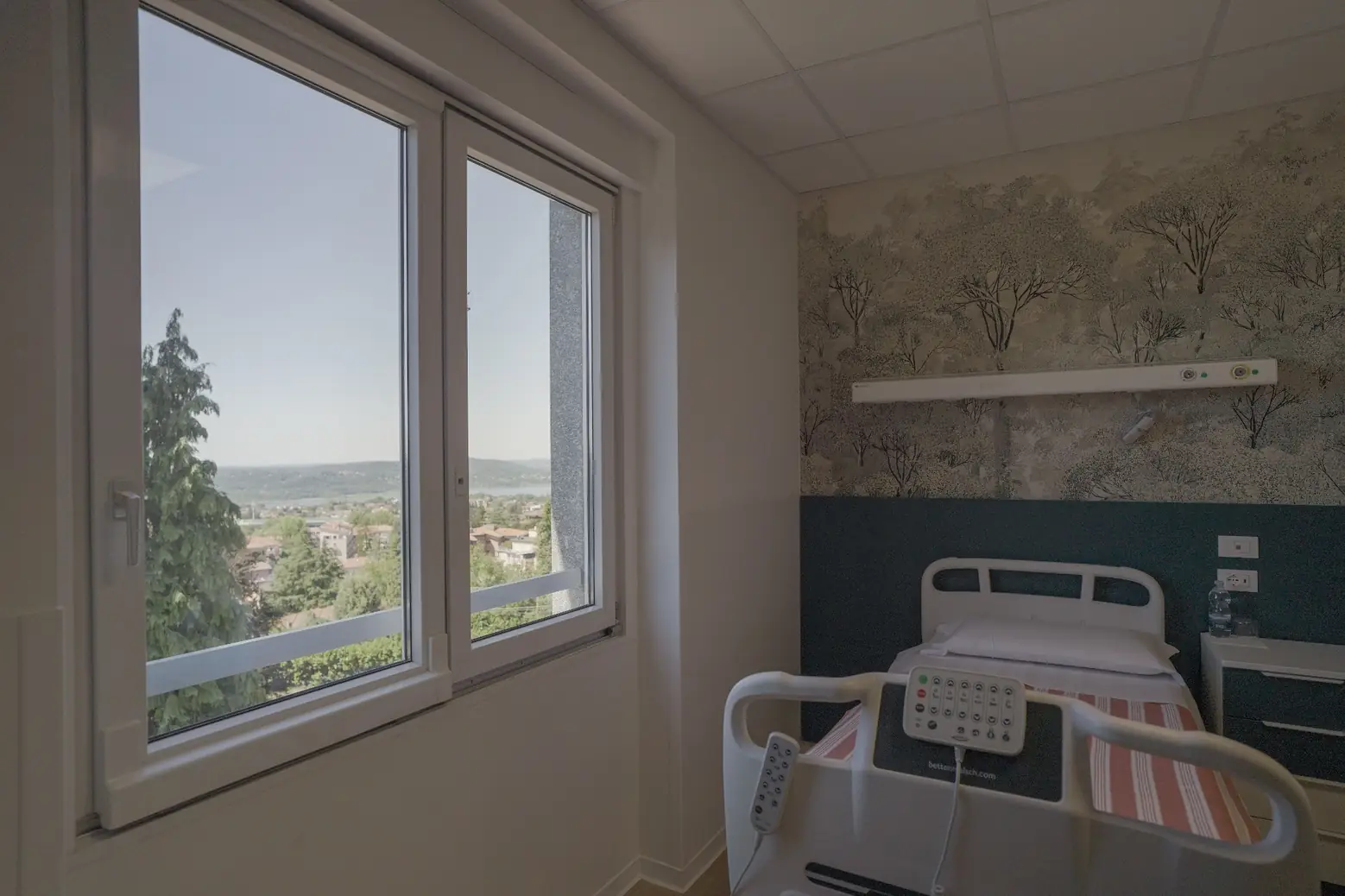 amera di degenza con letto e ampia finestra affacciata sul paesaggio di Varese